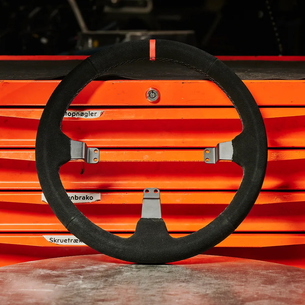 Asetek Racing rally-drift ratgrims i velour med diskformet design til racercykler og bilsport, set mod racermiljø.